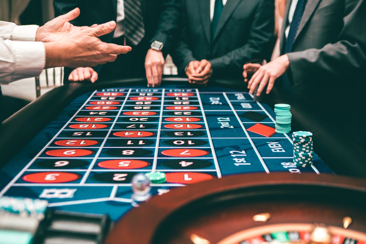 about-us Group of people playing roulette, placing bets in a casino setting.